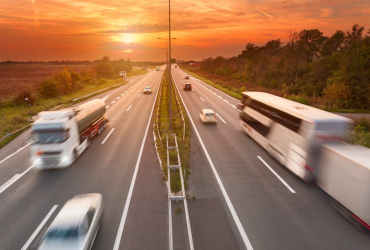 Foto panorâmica do tráfego de uma rodovia com ônibus e caminhões