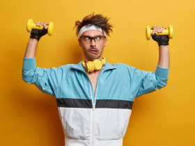 Jovem treina músculos das mãos com halteres, faz todos os esforços para levantar peso, faz reabilitação física, faz exercícios para os braços, posa em casa ginásio, vestido com roupas esportivas.