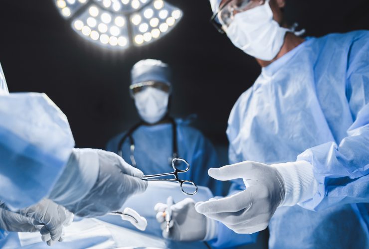 Close-up da equipe de cirurgia operando em um hospital moderno. Por insidecreativehouse