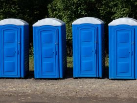 Fileira de banheiros químicos portáteis de várias cores colocados para um evento nas ruas da cidade. Por joaquincorbalan