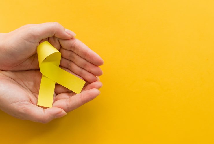 Foto de cima de uma mão feminina segurando uma fita amarela sobre fundo amarelo Por wirestock