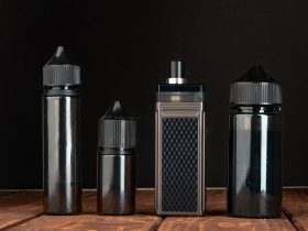 Vape e garrafas de líquido vape contra fundo preto Por FabrikaPhoto