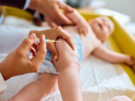 Close-up do médico dando vacina a um bebê no consultório do pediatra. Por drazenphoto