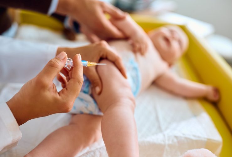 Close-up do médico dando vacina a um bebê no consultório do pediatra. Por drazenphoto