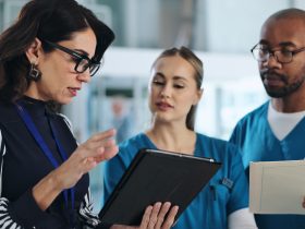 Equipe médica, tablet e reunião na clínica para aconselhamento, inovação e feedback com o relatório do paciente. Por YuriArcursPeopleimages