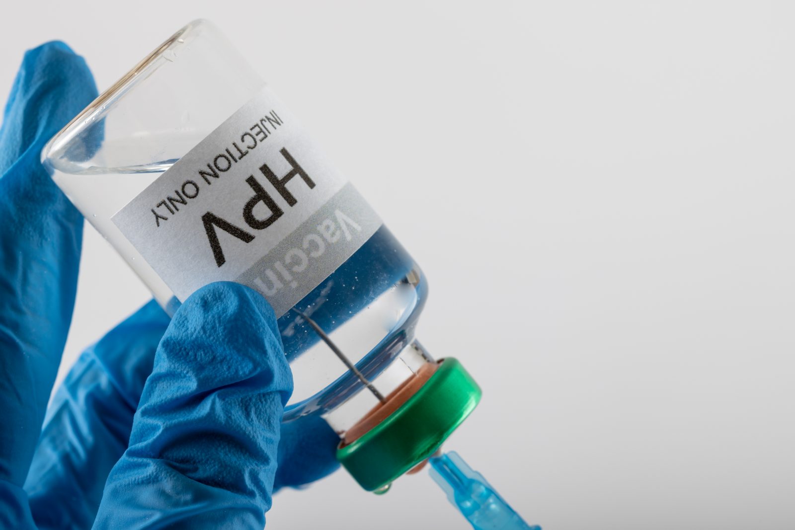 Composição da seringa de enchimento das mãos enluvadas do médico do frasco da vacina contra o HPV, em branco com espaço de cópia Por Wavebreakmedia