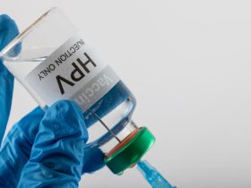 Composição da seringa de enchimento das mãos enluvadas do médico do frasco da vacina contra o HPV, em branco com espaço de cópia Por Wavebreakmedia