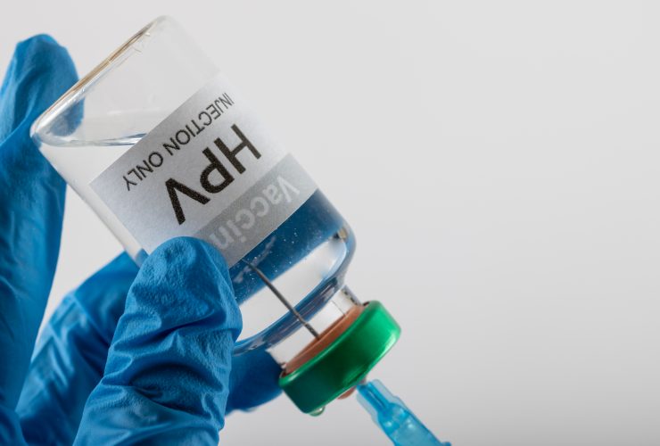 Composição da seringa de enchimento das mãos enluvadas do médico do frasco da vacina contra o HPV, em branco com espaço de cópia Por Wavebreakmedia