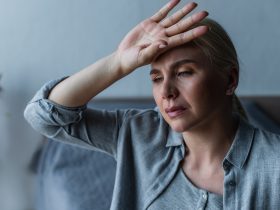 mulher loira cansada com menopausa sofrendo de calor no quarto Por LightFieldStudios