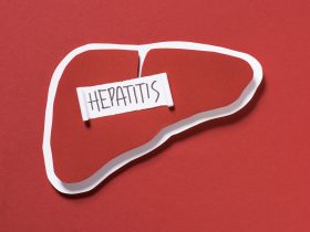vista superior do fígado e letras da hepatite em fundo vermelho, conceito do dia mundial da hepatite Por LightFieldStudios