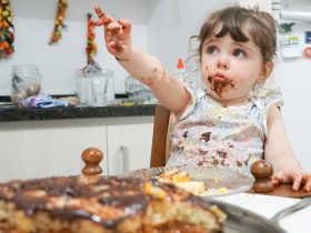 Criança comendo bolo de chocolate Por msandrioli