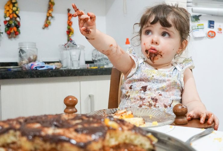 Criança comendo bolo de chocolate Por msandrioli