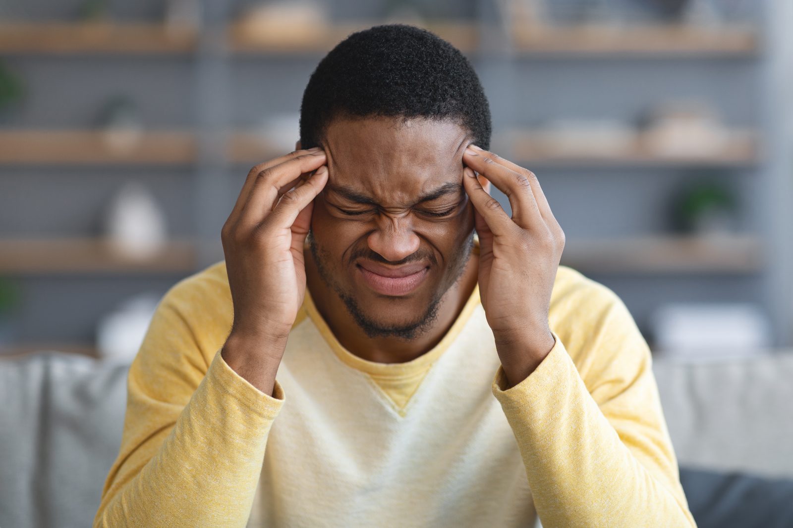 Closeup de um homem afro-americano com dor de cabeça Por Prostock-studio