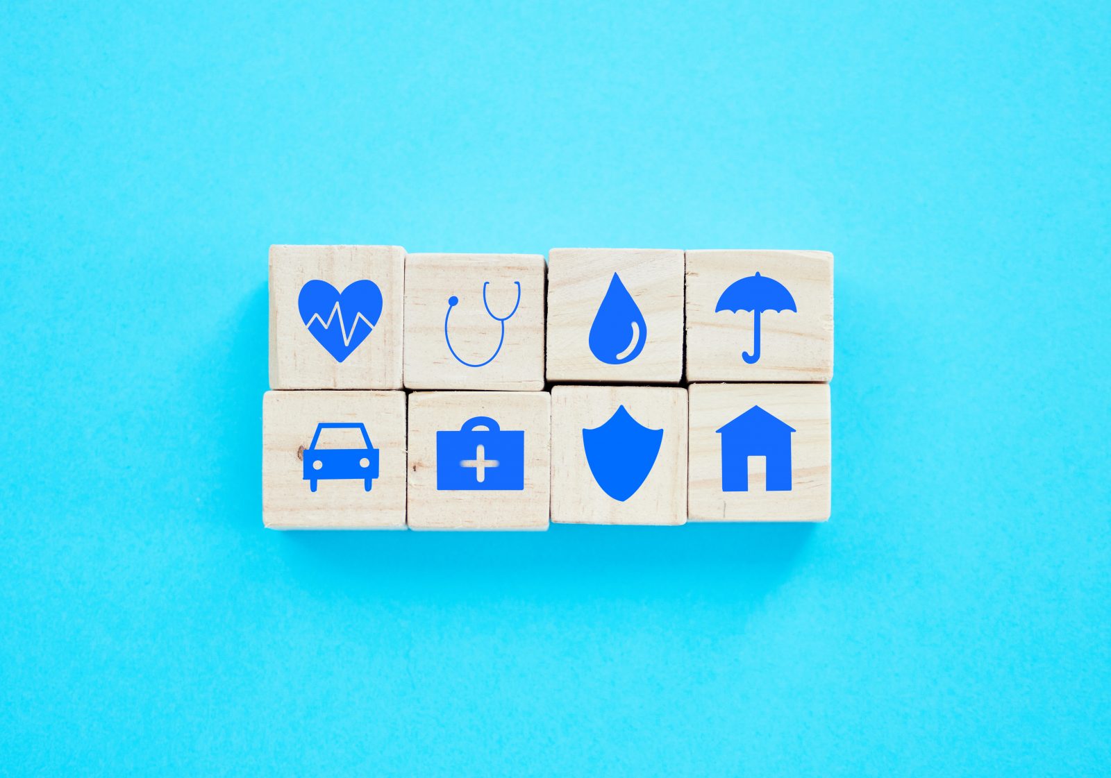 Foto de blocos de madeira com símbolos relacionados a seguros sobre um fundo azul Por YuriArcursPeopleimages