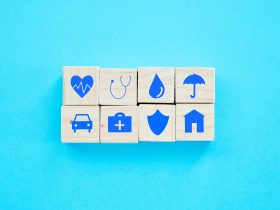 Foto de blocos de madeira com símbolos relacionados a seguros sobre um fundo azul Por YuriArcursPeopleimages