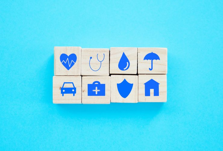 Foto de blocos de madeira com símbolos relacionados a seguros sobre um fundo azul Por YuriArcursPeopleimages