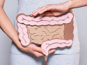 vista parcial da mulher segurando papel feito intestino grosso em fundo cinza Por LightFieldStudios