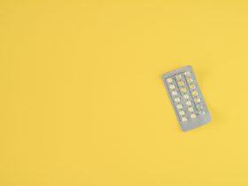 Pílulas anticoncepcionais orais femininas no fundo amarelo. Por SmitBruins