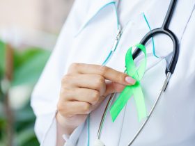 Fita verde na mão como símbolo de conscientização Câncer de linfoma Por maksymiv