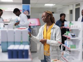Mulher afro-americana comprando vitaminas em farmácia, instrução de leitura Por DC_Studio