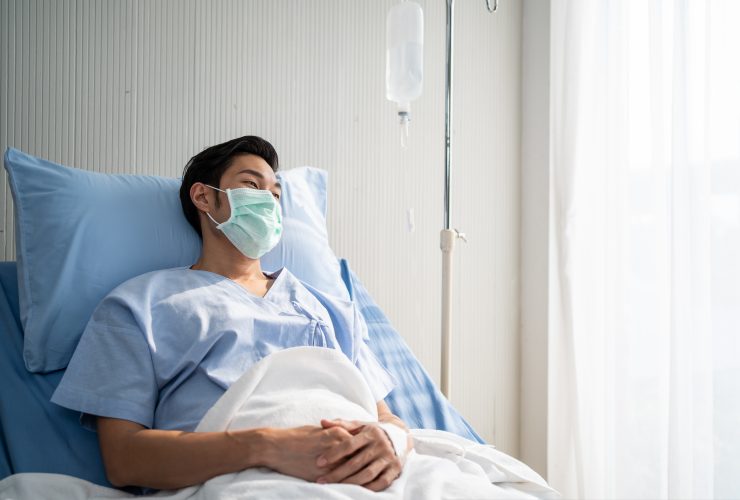 Paciente asiático do sexo masculino deitado na cama com máscara facial na sala de recuperação da enfermaria do hospital. Por s_kawee