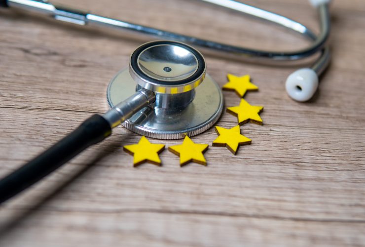 Imagem aproximada do estetoscópio e cinco estrelas na mesa de madeira com espaço de cópia. Por mohdizzuanbinroslan