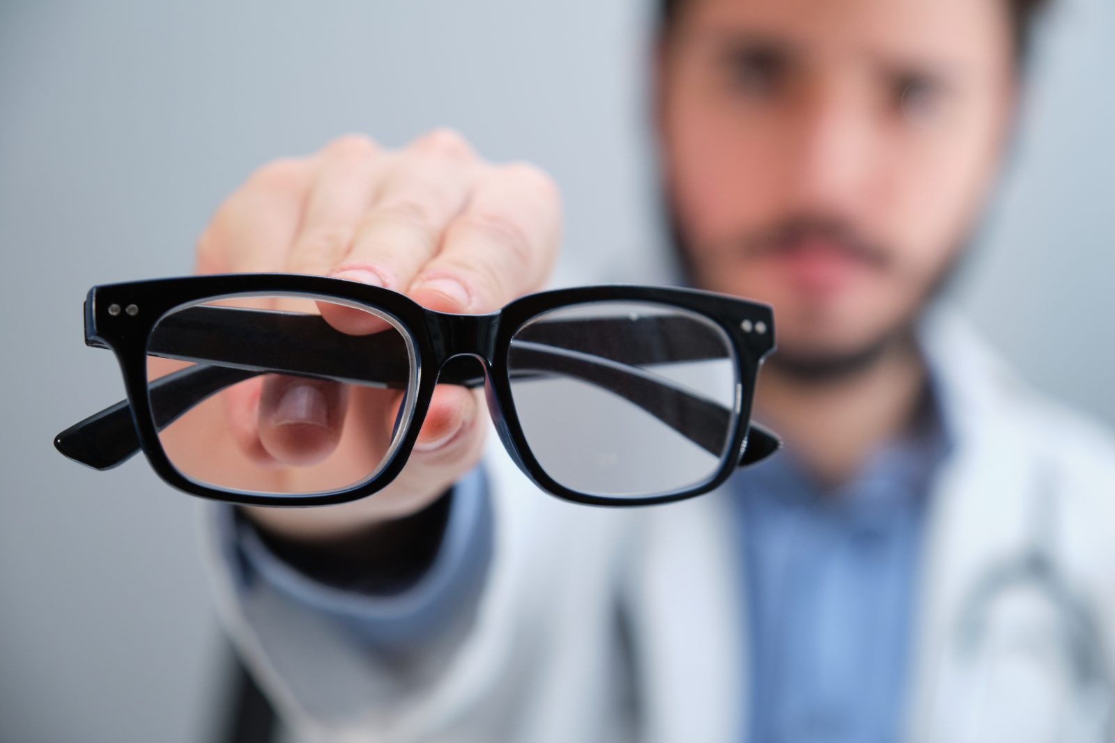 Médico irreconhecível sugerindo óculos para uma pessoa com problemas de visão. Por Ladanifer