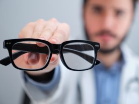 Médico irreconhecível sugerindo óculos para uma pessoa com problemas de visão. Por Ladanifer