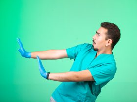 Médico de uniforme e máscara de mão se prevenindo Por 13people