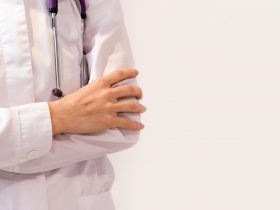 Médico de uniforme está com os braços cruzados sob o peito, sem rosto, close-up, conceito médico Por buzmakovatatyana