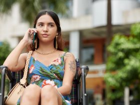 Mulher em cadeira de rodas falando no telefone Por DragonImages