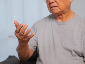 A mão de um homem idoso está tremendo por causa da doença de Parkinson. Por rthanuthattaphong