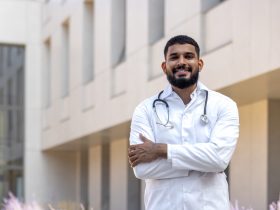 Retrato de um jovem estudante de medicina, um estagiário em pé do lado de fora do prédio médico e olhando Por voronaman111