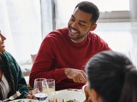 Amigos desfrutando de uma refeição festiva de Natal juntos, compartilhando histórias e risadas em casa Por LightFieldStudios