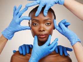 Retrato, mãos e cirurgia plástica para mudança com uma paciente negra em estúdio com um dorso cinza Por YuriArcursPeopleimages