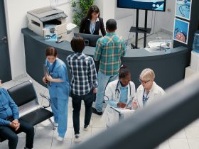 Médico sênior e médico afro-americano falando na recepção do hospital Por DC_Studio