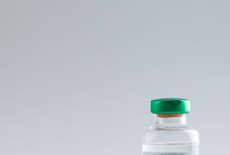 Composição vertical do frasco e seringa da vacina contra o HPV em fundo cinza com espaço de cópia Por Wavebreakmedia