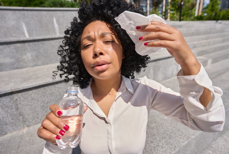 Mulher multirracial sentada na escada atormentada pelo calor intenso Por svitlanah