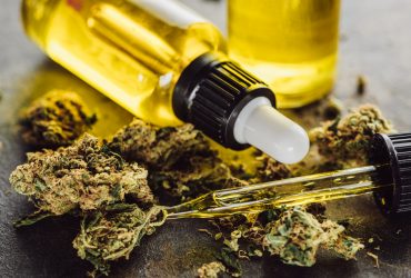 visão aproximada de botões de maconha medicinal, frasco e conta-gotas com óleo de cânhamo na superfície da pedra Por LightFieldStudios