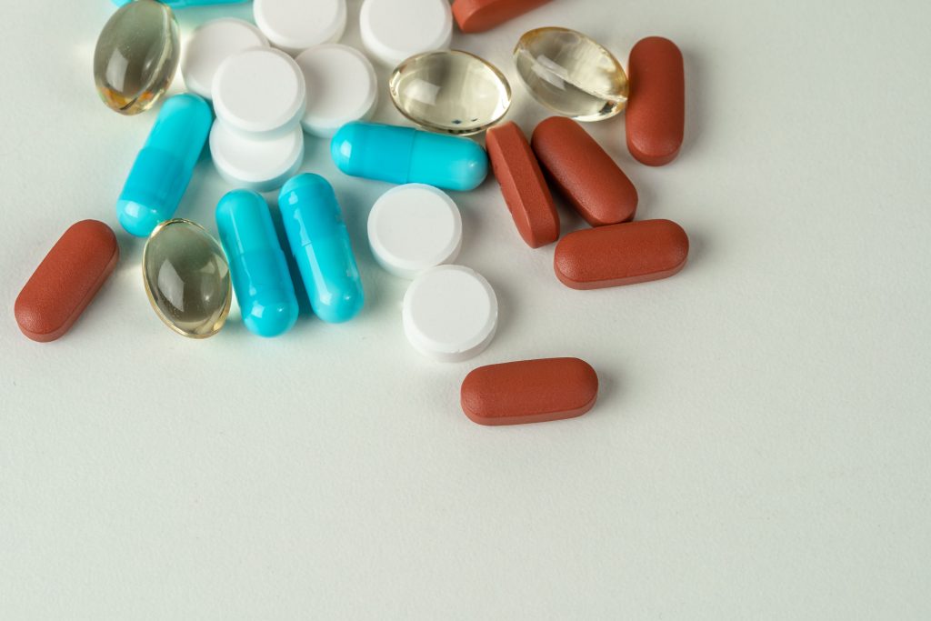 Detalhe dos diferentes tipos de medicamentos na mesa. Conceito de tratamento médico, cuidados de saúde. Por wirestock