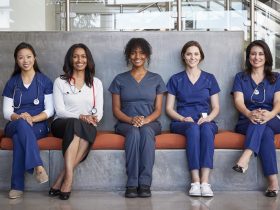 Profissionais de saúde do sexo feminino sentadas em um hospital, de corpo inteiro Por monkeybusiness