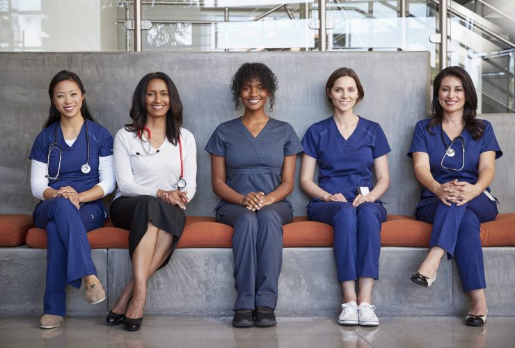 Profissionais de saúde do sexo feminino sentadas em um hospital, de corpo inteiro Por monkeybusiness