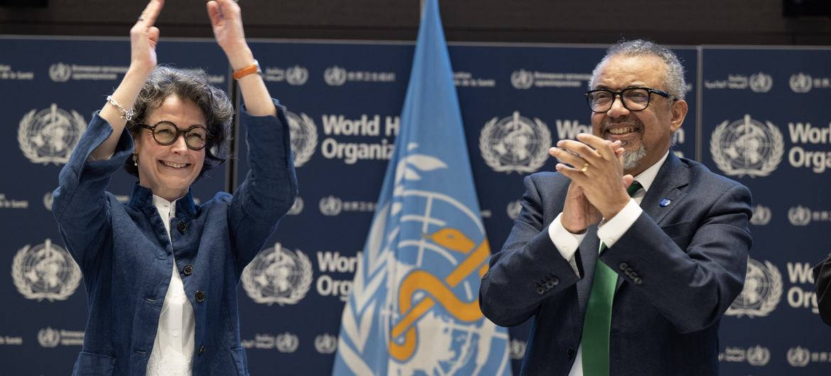 O diretor-geral da OMS, Tedros Adhanom Ghebreyesus (à direita), e a copresidente do INB, Anne-Claire Amprou, da França (à esquerda), comemoram a conclusão das negociações nas primeiras horas de 16 de abril de 2025. Foto de Christopher Black para a OMS