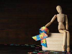 Fita com peças de quebra-cabeça coloridas e figura de madeira em fundo escuro, lugar para texto Por AtlasComposer