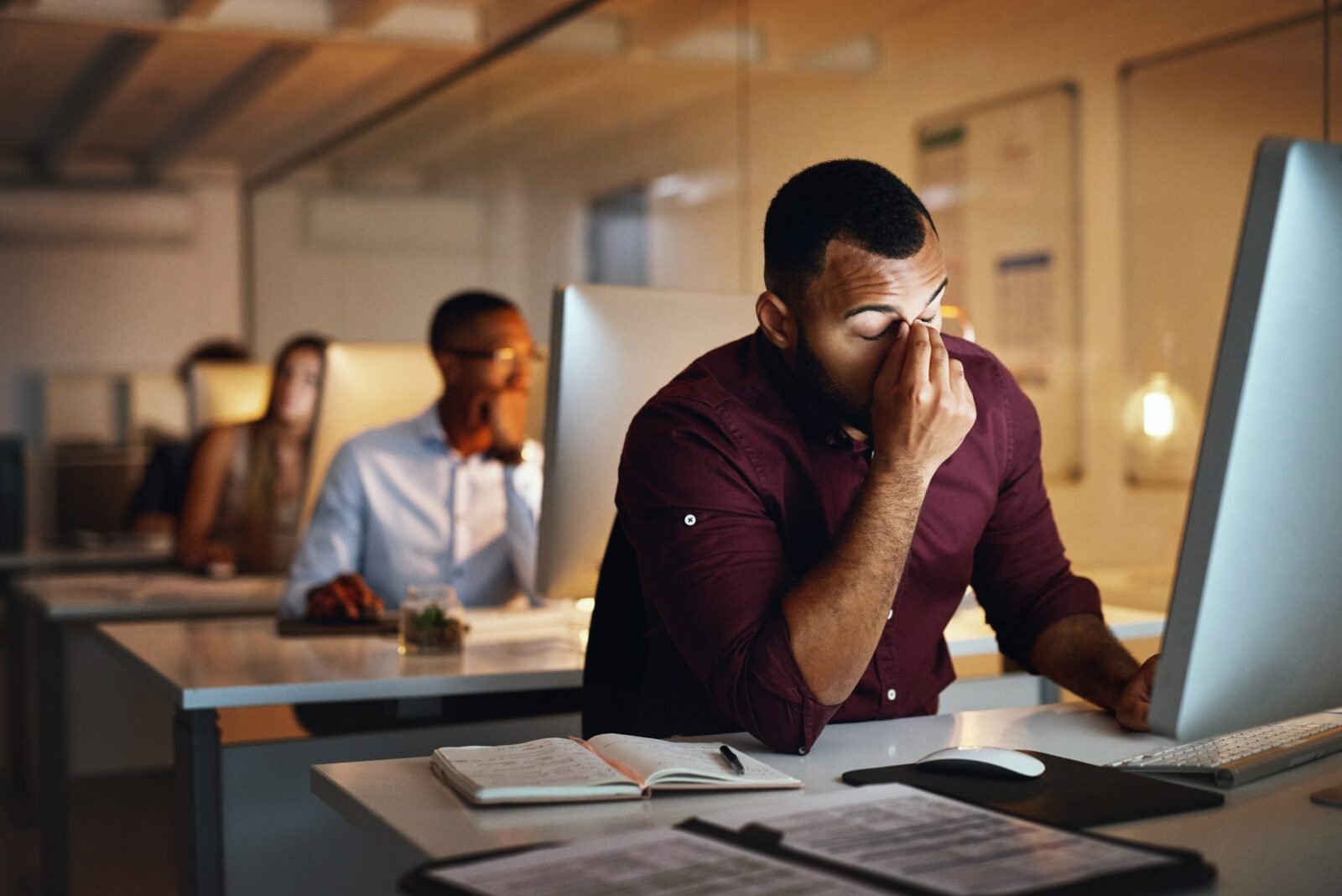 Foto de um jovem empresário parecendo estressado enquanto trabalhava até tarde em um escritório Por YuriArcursPeopleimages