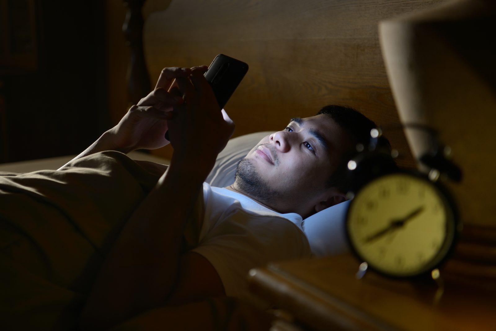 Jovem usando um smartphone em sua cama à noite Por amenic181