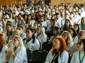 Na imagem estão presentes médicos utilizando jaleco branco, sentados em poltronas.